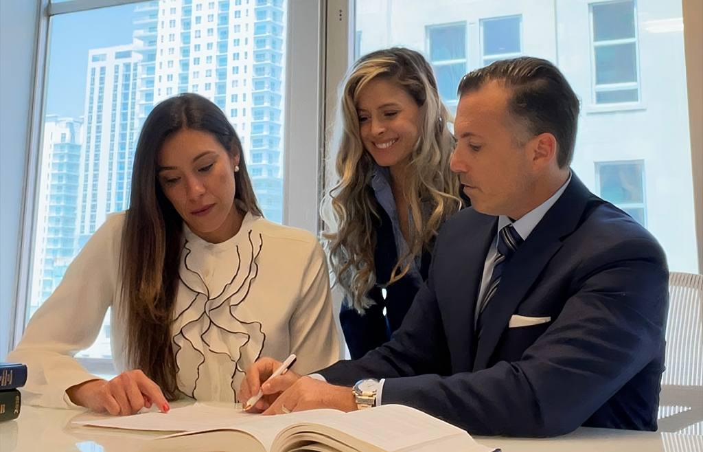Lawyers at Perkins Law Offices assisting a client with legal documents in a modern office setting, emphasizing personal injury legal services in Miami.