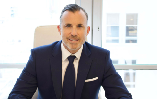 Alex Perkins, Miami personal injury attorney, seated in office, wearing a navy suit and tie, representing legal expertise and support for injury cases.