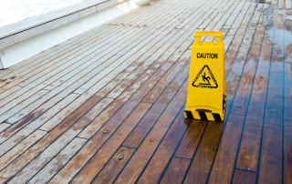 Caution sign on wet wooden deck indicating slip hazard, relevant to personal injury law and slip and fall incidents in Doral.