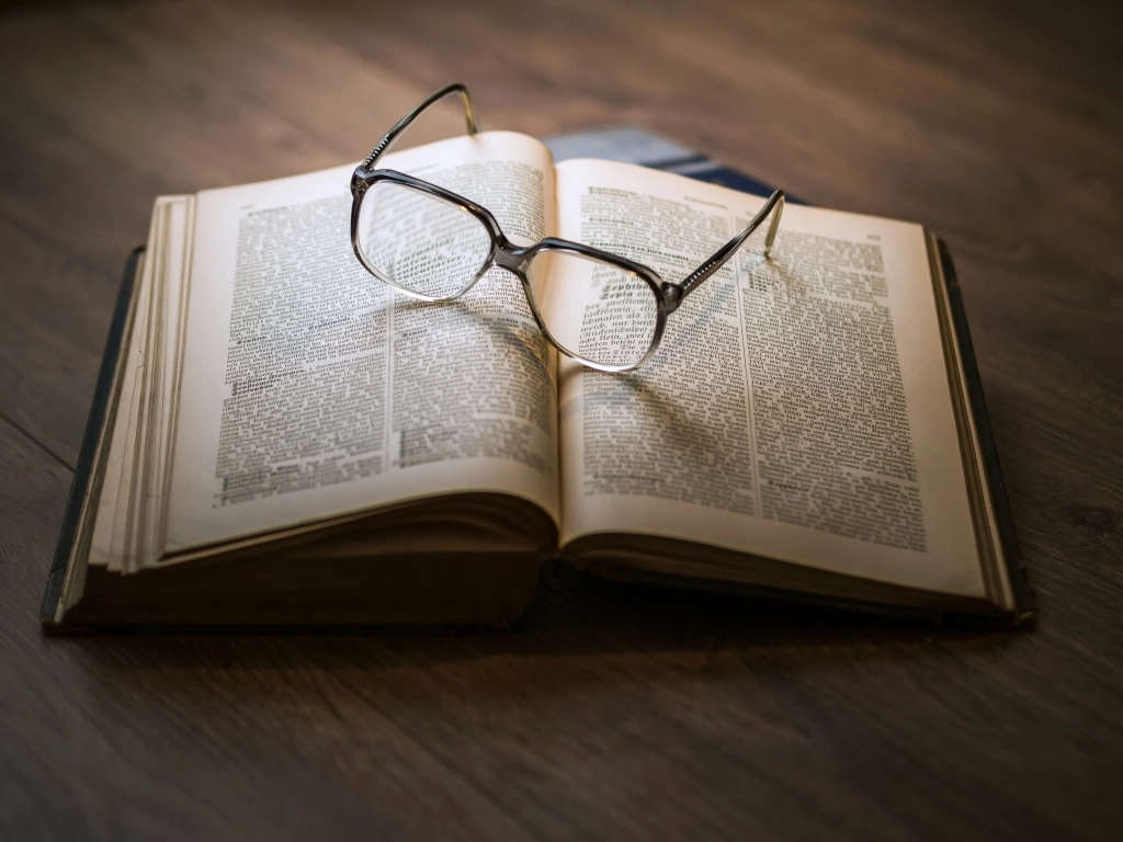 Open book with reading glasses on top, symbolizing legal study and understanding of car accident statutes and limitations.