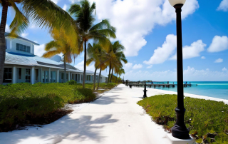 Scenic view of a palm tree-lined walkway along the beach in Key West, featuring a clear blue ocean and a wooden pier in the distance, relevant to personal injury law discussions in coastal settings.