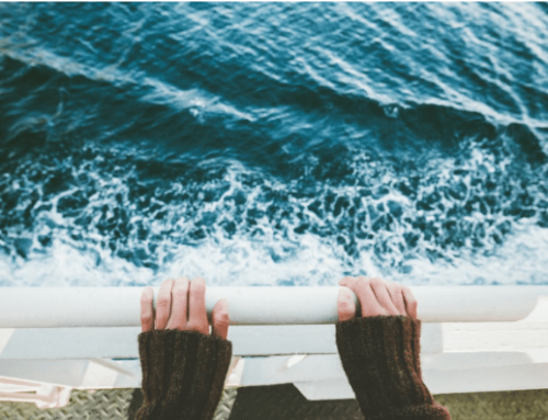 Hands resting on a railing overlooking ocean waves, symbolizing the cruise experience and potential risks associated with cruise ship injuries.